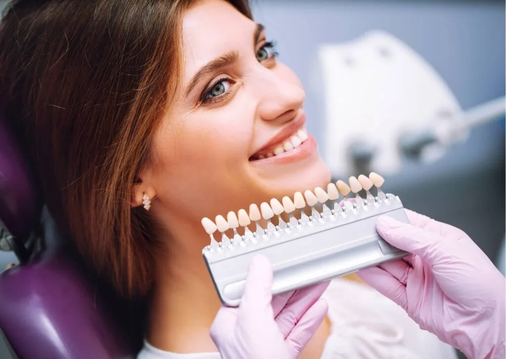 Dentist using a tooth shade guide to explain expected teeth whitening results during a cosmetic consultation